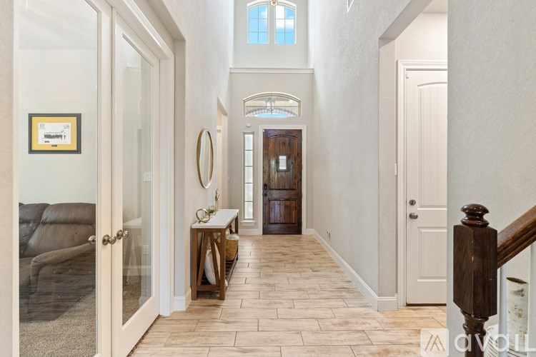 A hallway with a wooden floor and a staircase on the right.