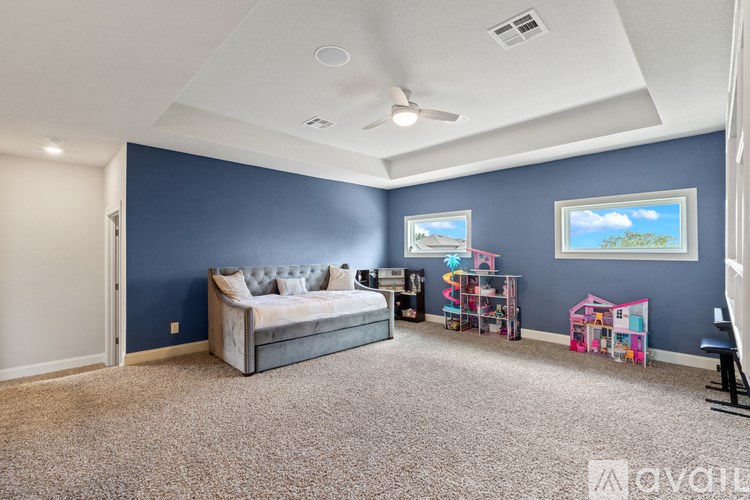 A spacious room with a bed, a play area, and a ceiling fan.