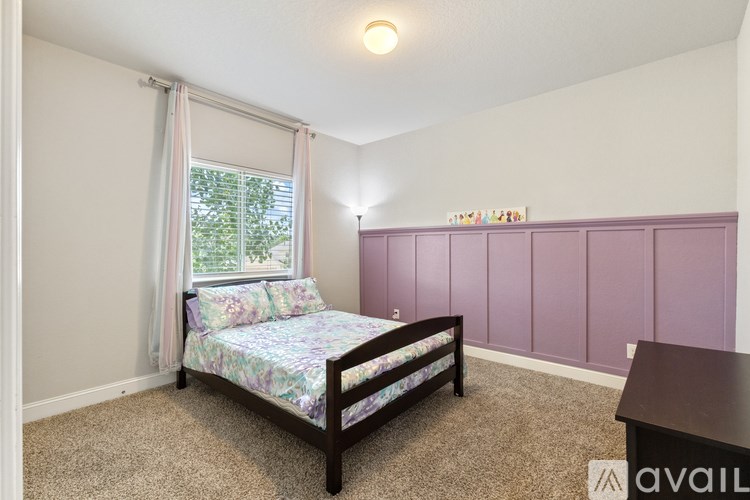 A bedroom with a bed, a window with curtains, and a purple wall.