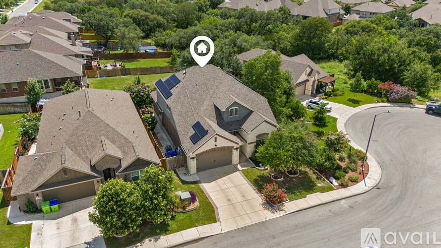 A bird's eye view of a neighborhood with a house in the center that has a solar panel on the roof.
