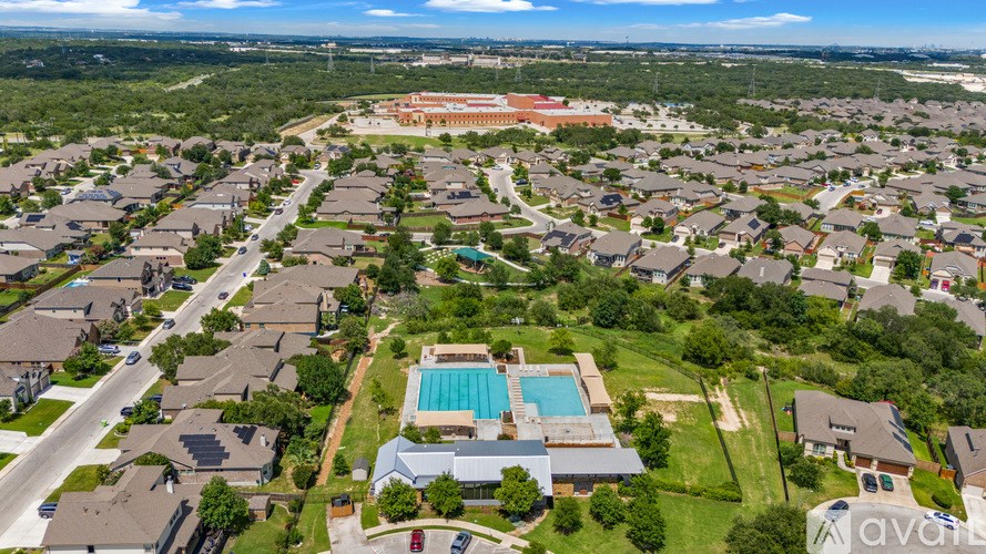 A bird's eye view of a residential area with houses, a swimming pool, and a road.