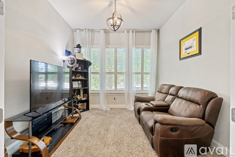 A living room with a brown leather couch and a flat screen TV.