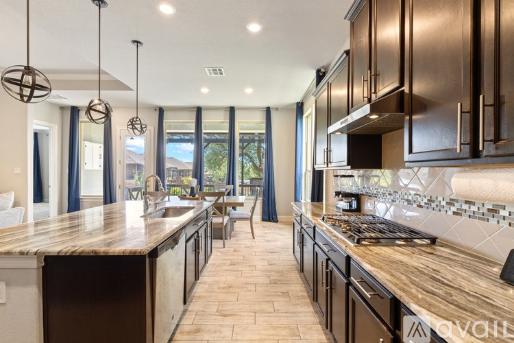 A modern kitchen with dark wood cabinets and a marble backsplash.