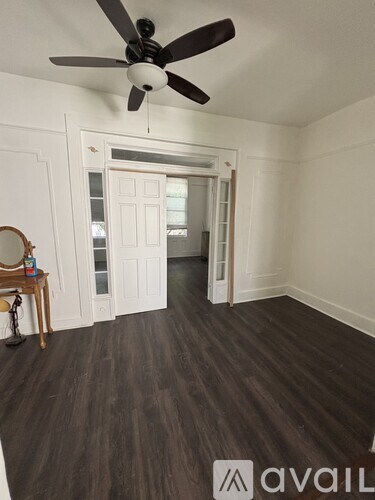 A room with a ceiling fan and wooden flooring.