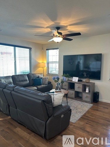 A living room with a large couch and a flat screen TV mounted on the wall.
