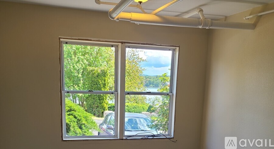 A room with a window showing a view of a street with cars and trees.