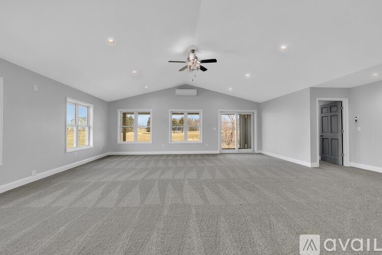A spacious room with a carpeted floor and a ceiling fan.