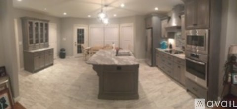 A spacious kitchen with a marble countertop and a dining area with a table set for two.