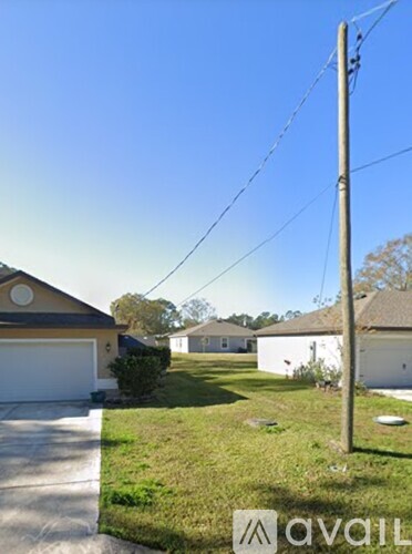 A house with a white garage door is situated in a grassy area.