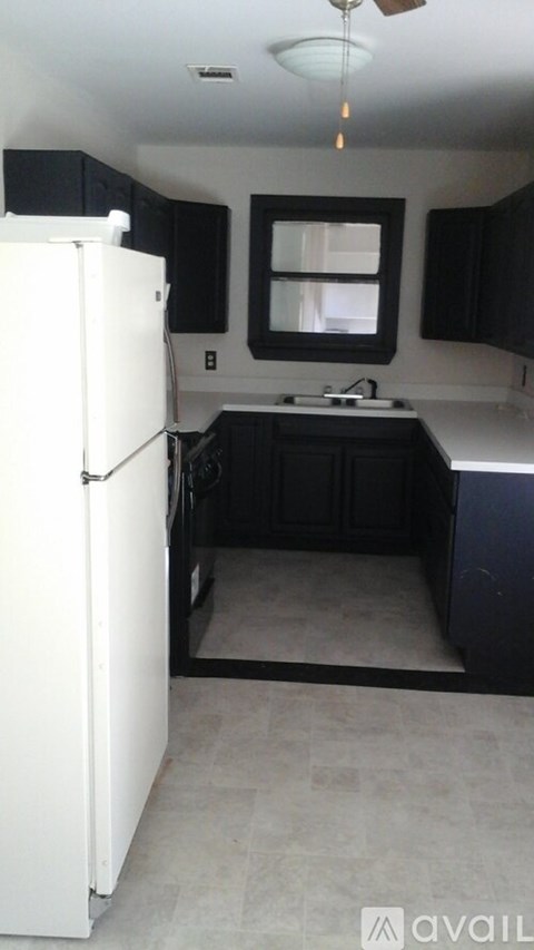 A kitchen with a white refrigerator and black cabinets.