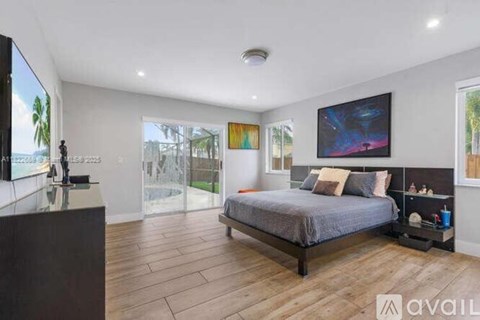 A bedroom with a large bed and a television on the wall.