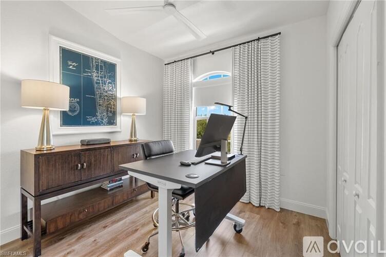 A room with a desk, chair, and two lamps.