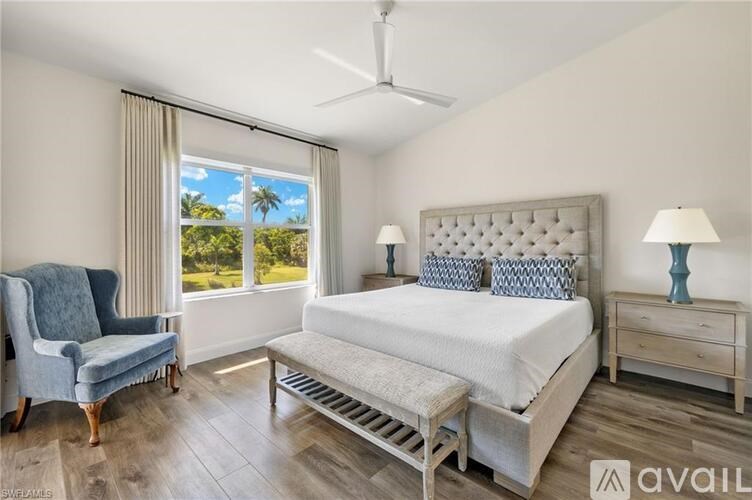 A bedroom with a large bed, a chair, and a window with a view of the outdoors.