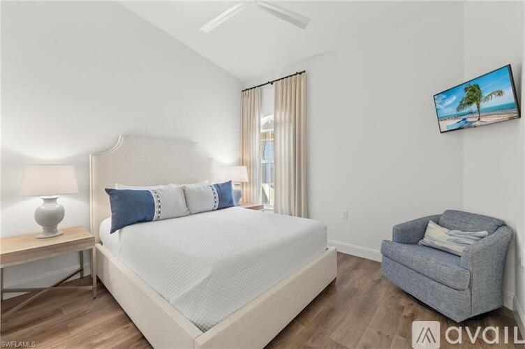 A bedroom with a large bed, a chair, and a television mounted on the wall.