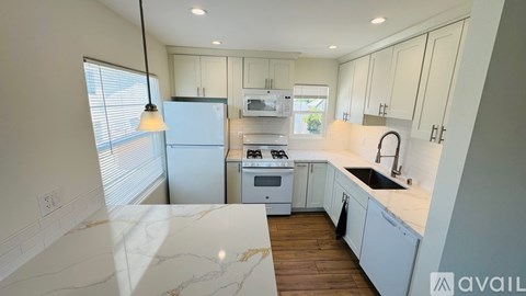 A kitchen with white cabinets and a marble countertop.