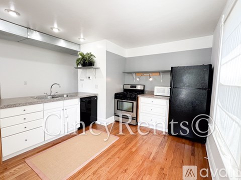 A kitchen with white cabinets and a black refrigerator.