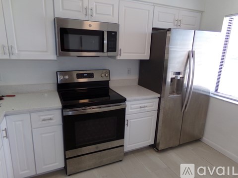 A kitchen with white cabinets and a stainless steel refrigerator.