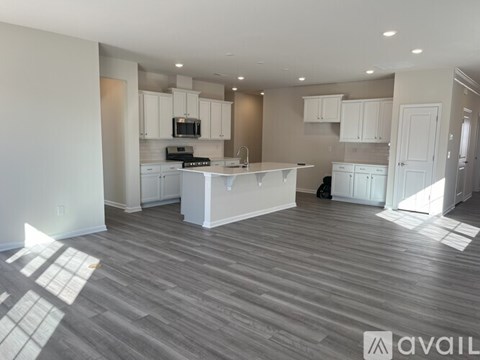 A spacious kitchen with white cabinets and a wooden floor.