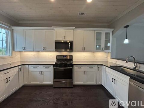 A kitchen with white cabinets and a black stove top oven.