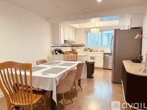 A kitchen with a table and chairs in the foreground and a refrigerator in the background.