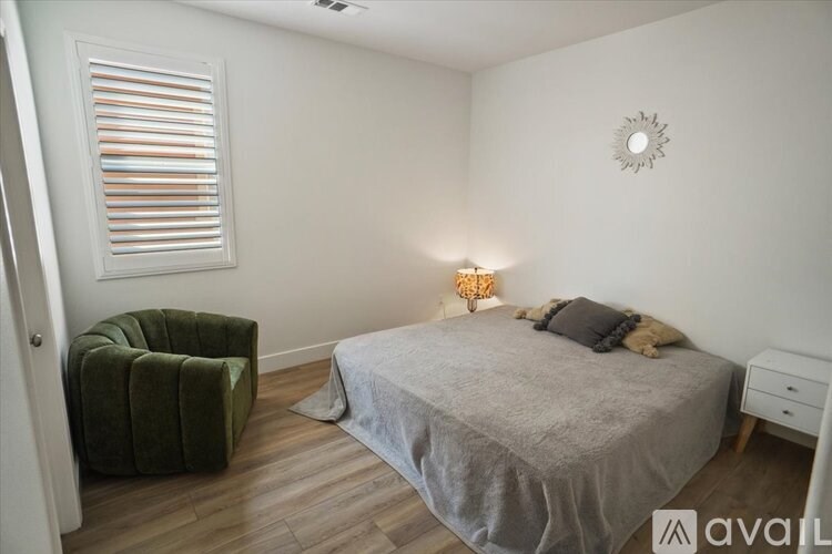 A bedroom with a bed, a chair, and a wall clock.