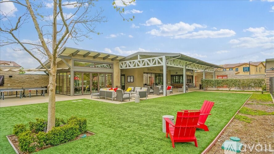 A sunny day at a community clubhouse with red chairs and a green lawn.