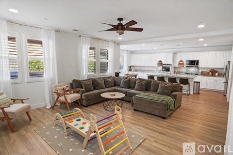 A living room with a grey couch and a wooden rocking chair.