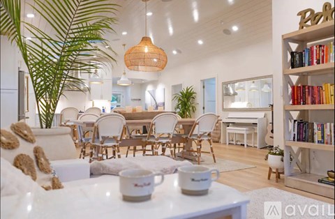 A living room with a dining table and chairs, a bookshelf, and a potted plant.
