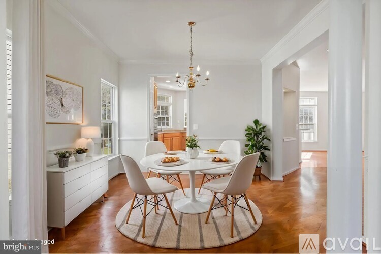 A dining room with a round table and white chairs.