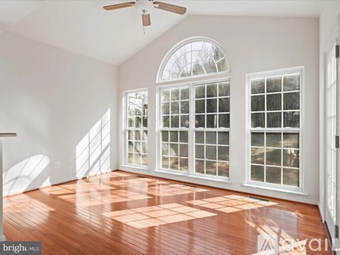 A room with a ceiling fan and a large window with a view of trees.