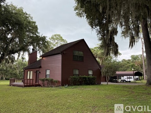A red house with a porch and a tree in front.