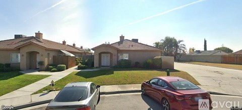 A red car is parked in front of a house with a Google car parked in front of it.