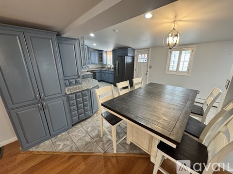 A kitchen with a table and chairs in the foreground and a refrigerator in the background.