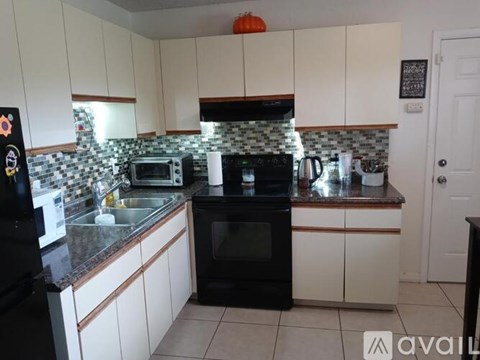 A kitchen with black appliances and white cabinets.