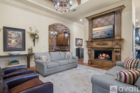 A living room with a grey couch, a fireplace, and a painting on the wall.