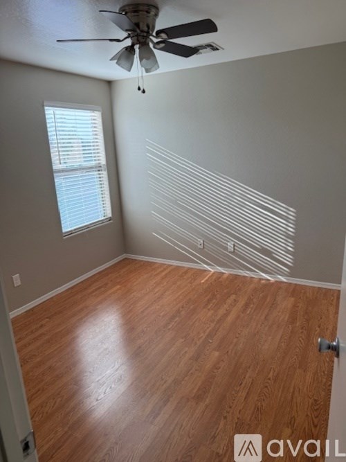 A room with a ceiling fan and wooden flooring.