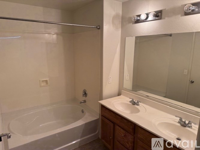 A bathroom with a white tub, sink, and mirror.