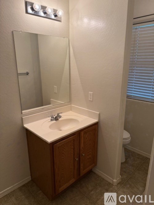 A bathroom with a sink, mirror, and cabinet.