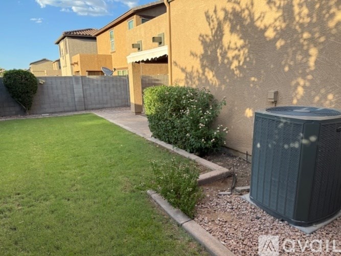 A backyard with a green lawn, a grey water tank, and a brown fence.