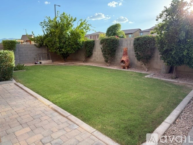 A backyard with a green lawn and a brick pathway.