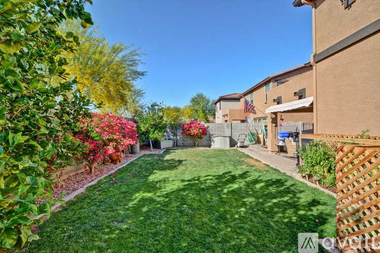 A well-maintained lawn with a fence and flowering shrubs.