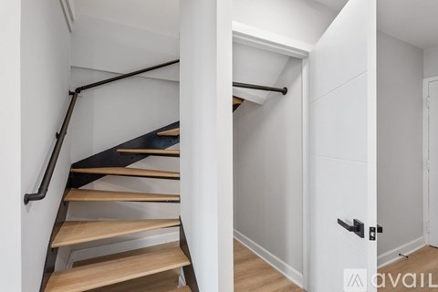 A set of stairs with a black handrail and wooden steps.