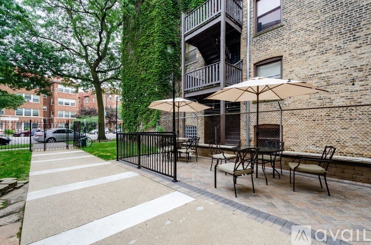 A patio with a table and chairs is surrounded by a black fence.