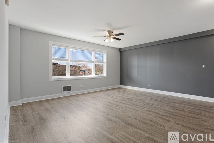 A room with a ceiling fan and a window overlooking a backyard.