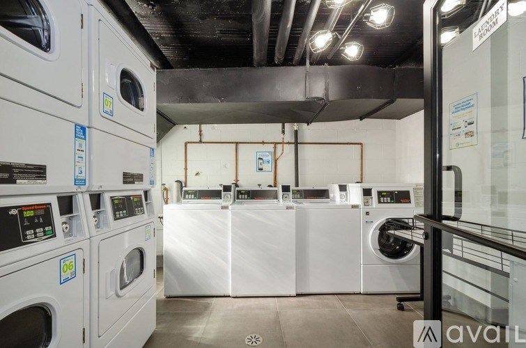 A row of industrial washing machines are lined up in a laundry facility.