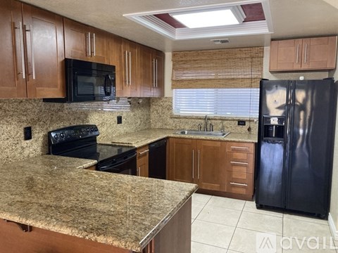 A kitchen with granite countertops and a black refrigerator.
