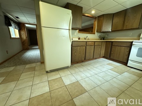 A kitchen with a white refrigerator and wooden cabinets.