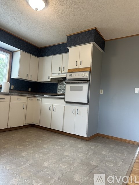 A kitchen with white cabinets and a tiled floor.