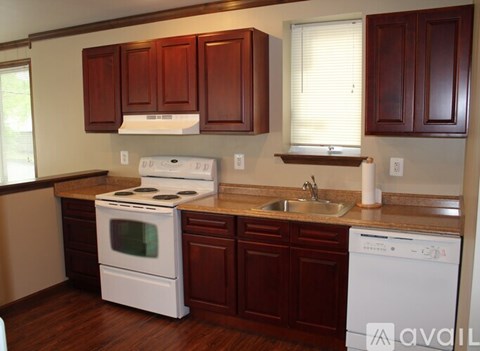 A kitchen with brown cabinets and white appliances.