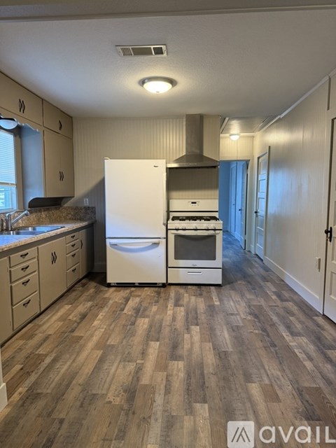 A kitchen with a white refrigerator and wooden flooring.